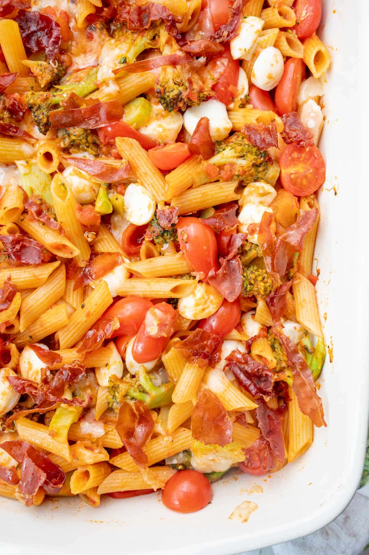 Cheesy Tomato Broccoli Pasta with Crispy Prosciutto in a white baking dish.