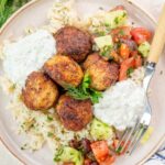 Greek chicken meatballs with rice and tzatziki on a beige plate.