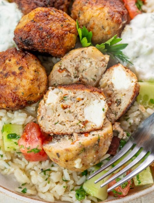 Greek chicken meatballs with rice and tzatziki on a plate.