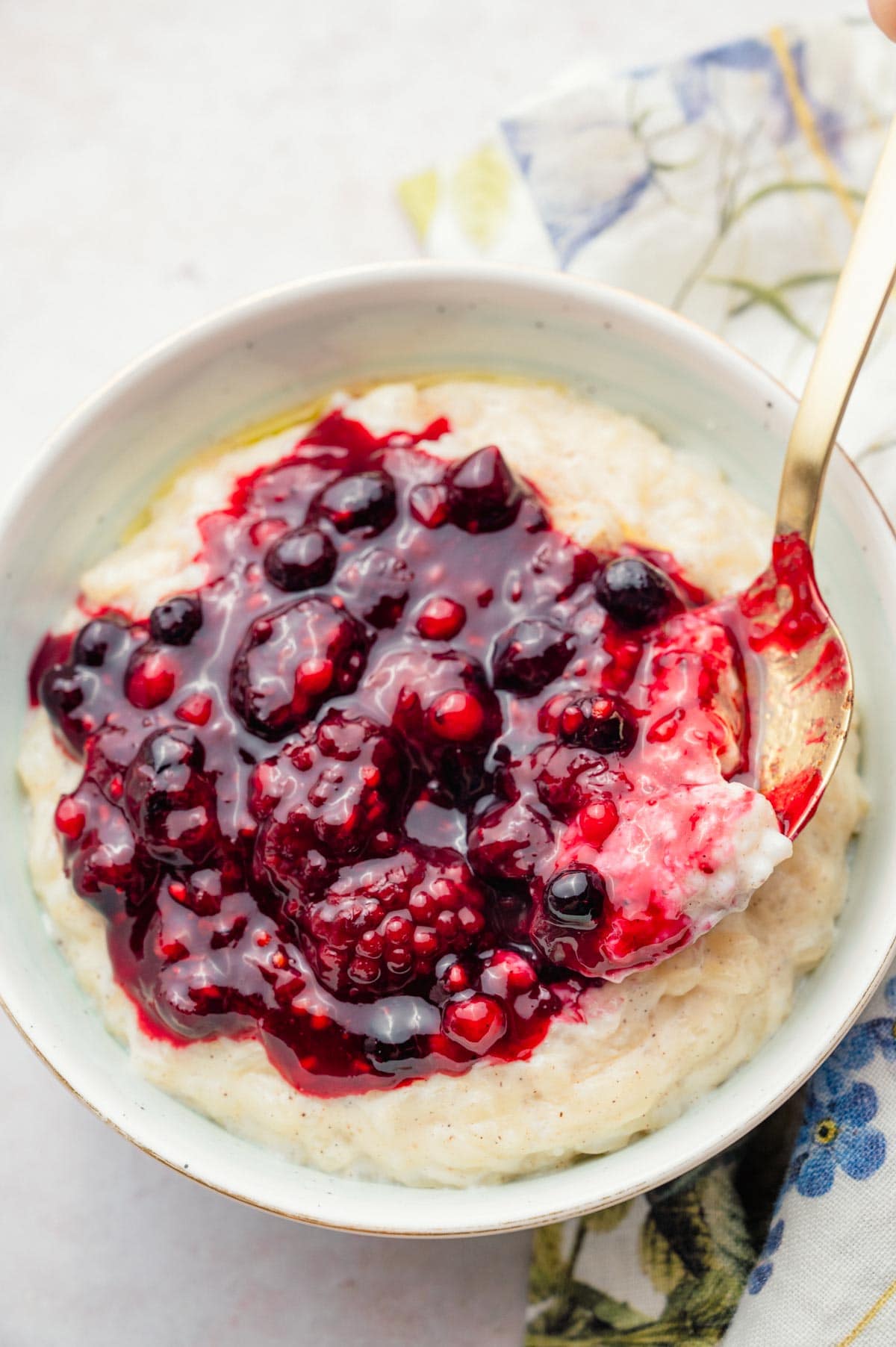 Milchreis in a white bowl topped with berry compote (Rote Grütze).