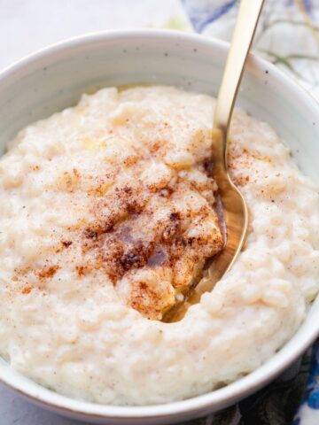 Milchreis in a white bowl topped with cinnamon sugar.