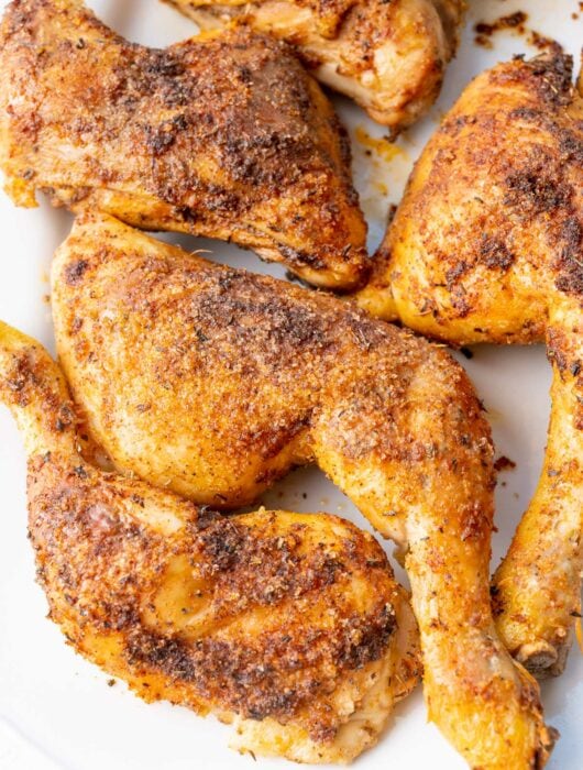 Baked chicken leg quarters on a white plate.