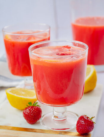 Two glasses with strawberry lemonade on a marble board.