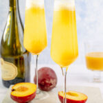 Two glasses with peach bellini on a stone board.