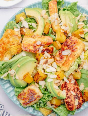 Halloumi salad with pineapple and avocado on a blue plate.