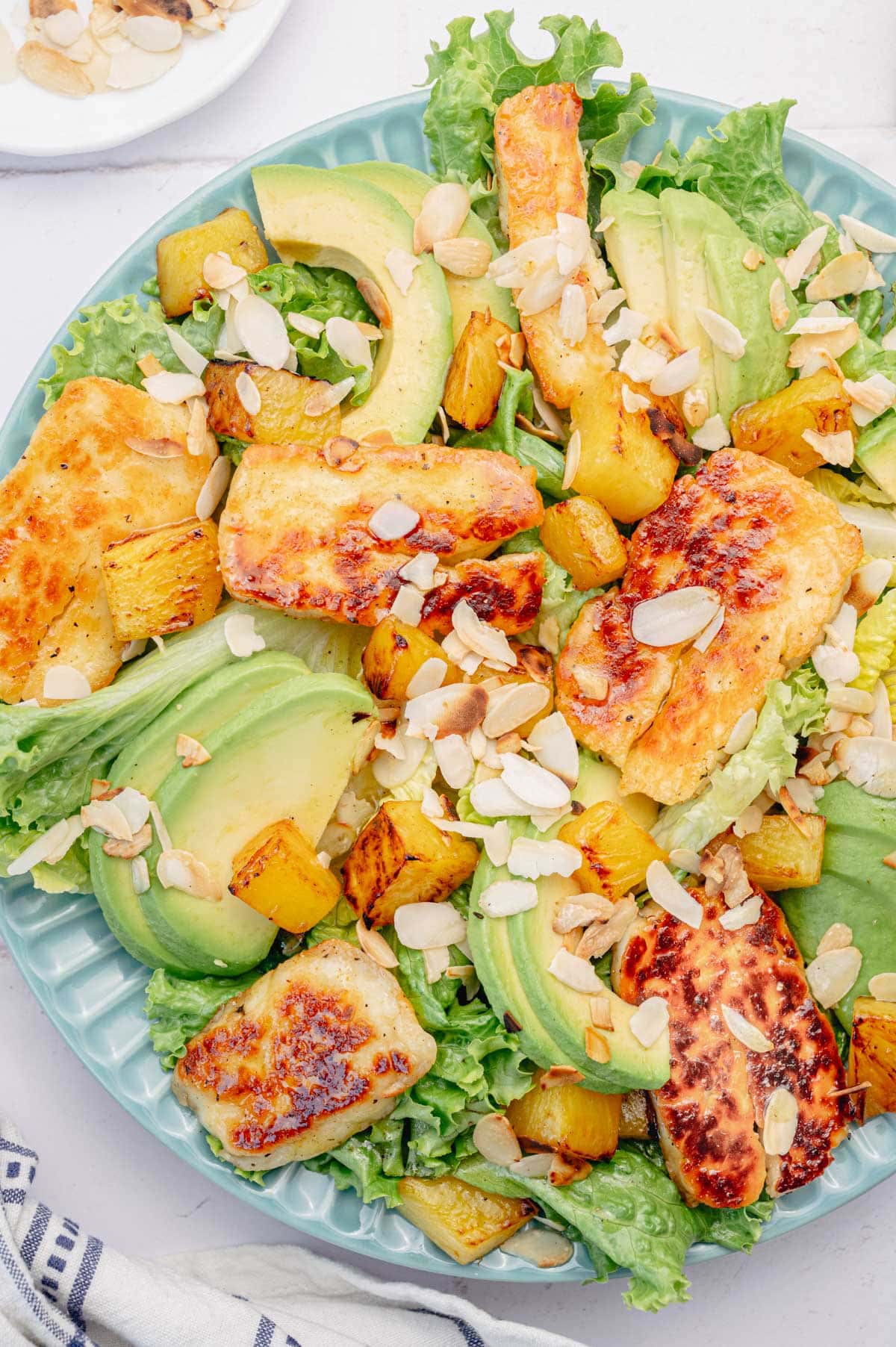 Halloumi Salad with pineapple and avocado on a blue plate.