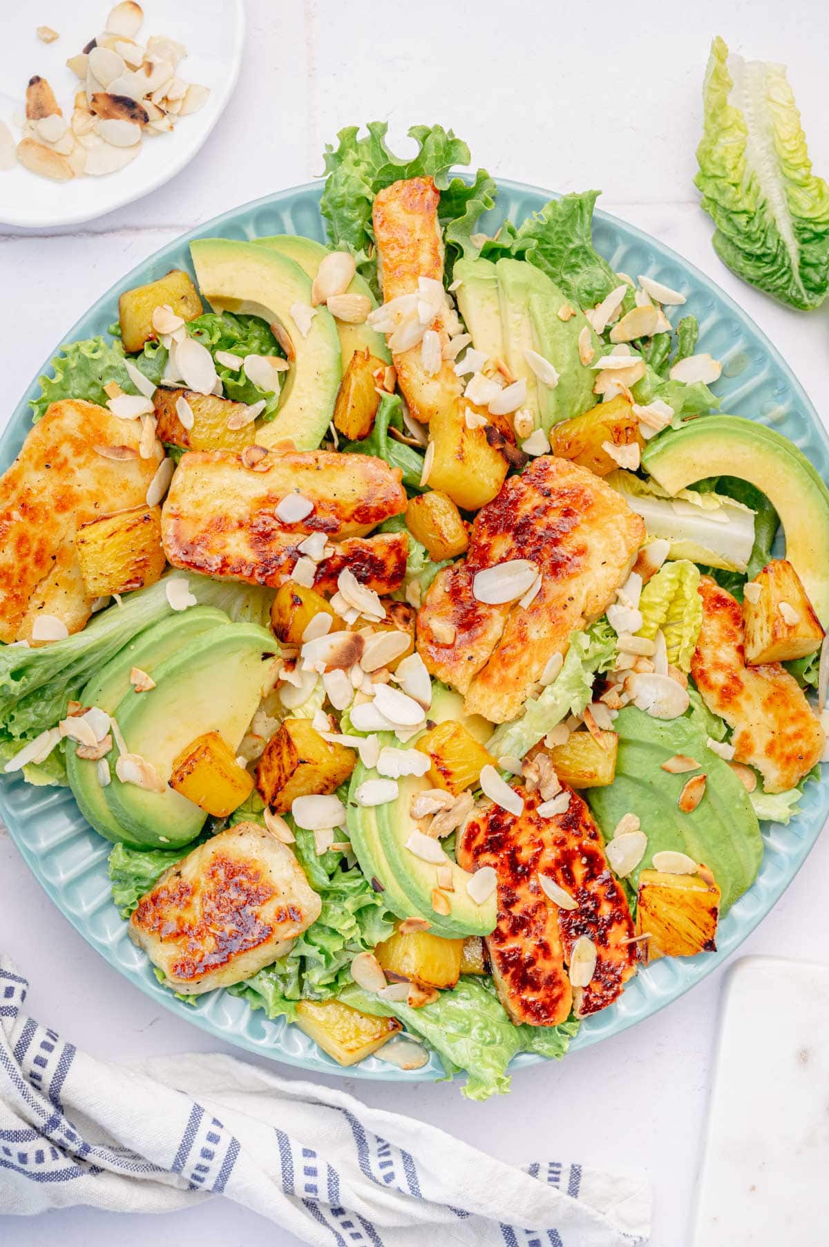 An overhead photo of Halloumi Salad with pineapple and avocado on a blue plate.