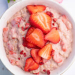 Strawberries and Cream Oatmeal in a white bowl topped with sliced strawberries.