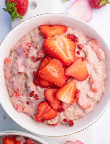 Strawberries and Cream Oatmeal in a white bowl topped with sliced strawberries.