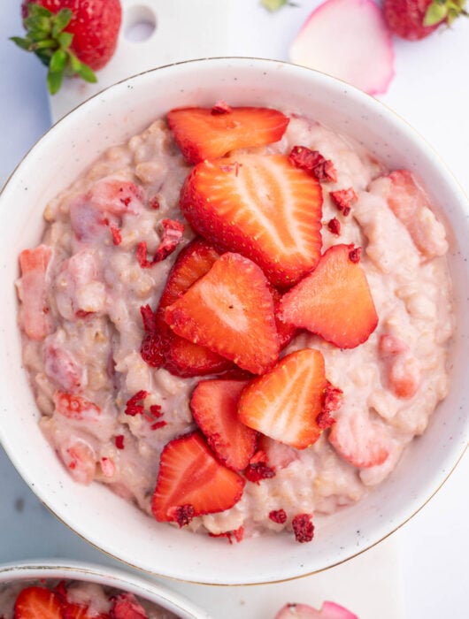 Strawberries and Cream Oatmeal in a white bowl topped with sliced strawberries.