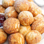 Aebleskiver Danish pancake balls on a beige plate dusted with powdered sugar.