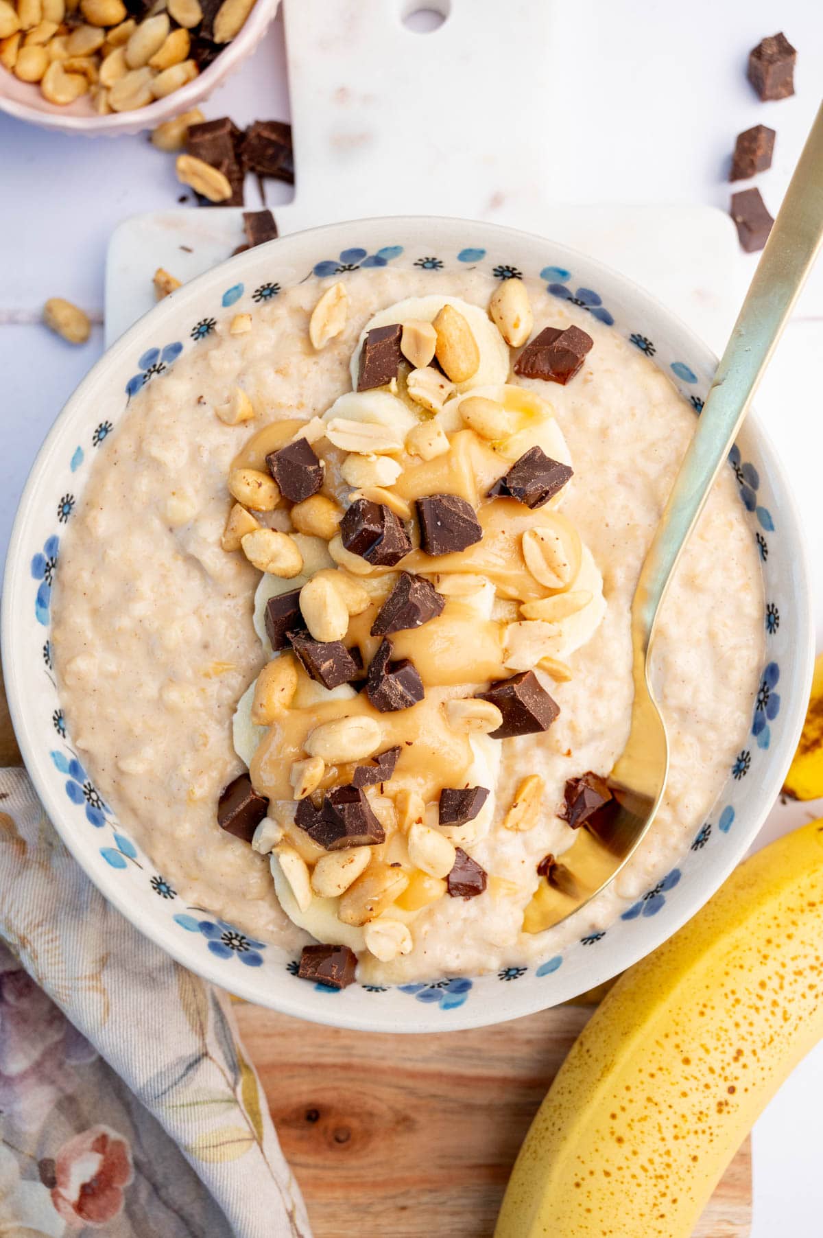 An overhead photo of banana peanut butter oatmeal in a white bowl.