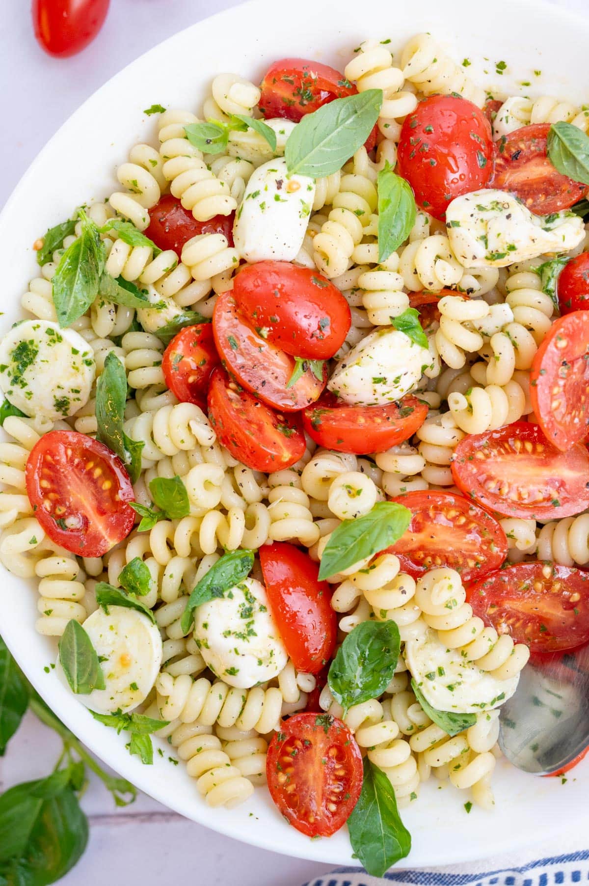An overhead photo of Caprese pasta salad in a white bowl.
