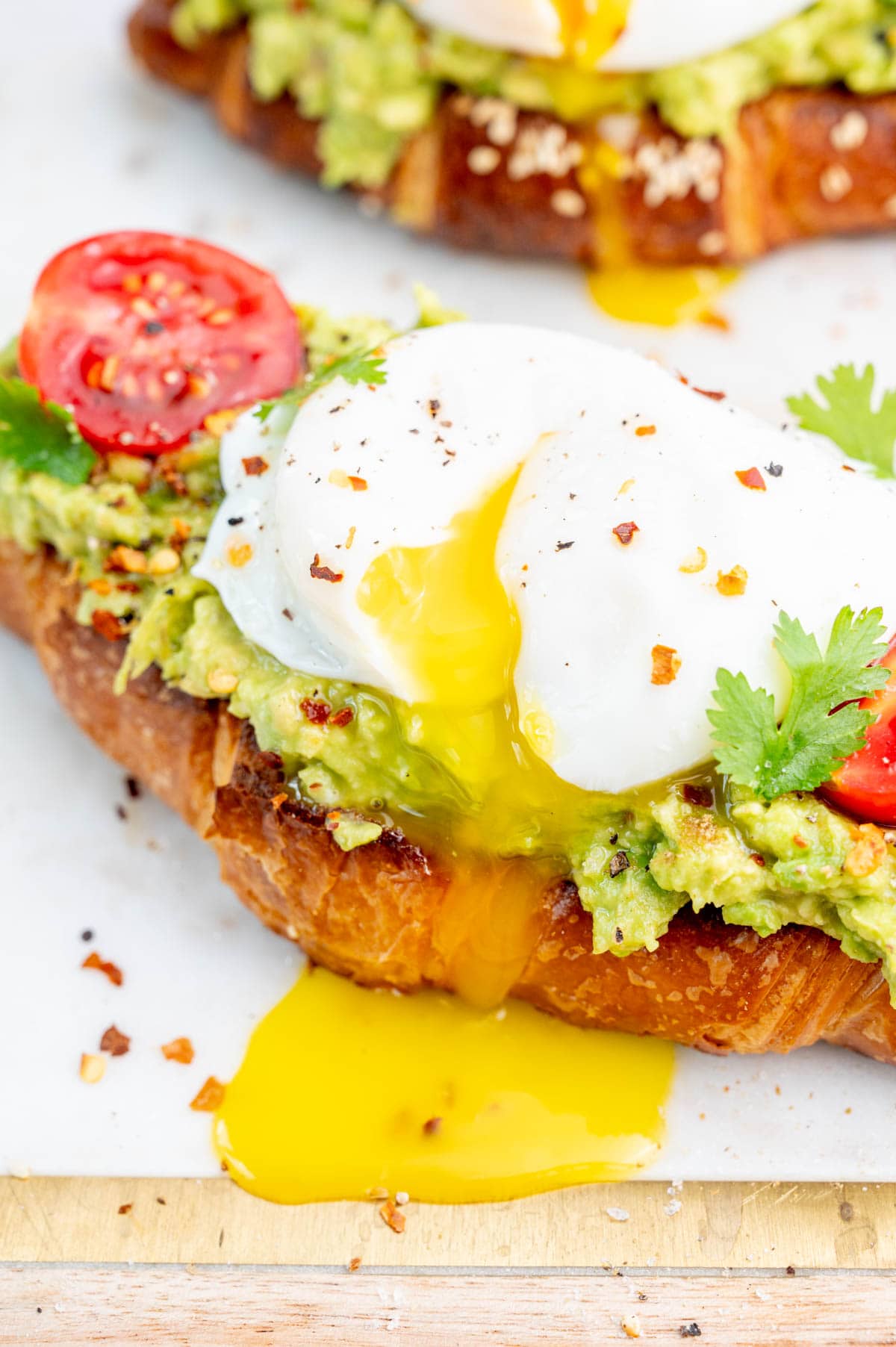 A close up photo of a runny yolk on an avocado egg toast.