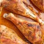 Baked turkey drumsticks in a white baking dish.