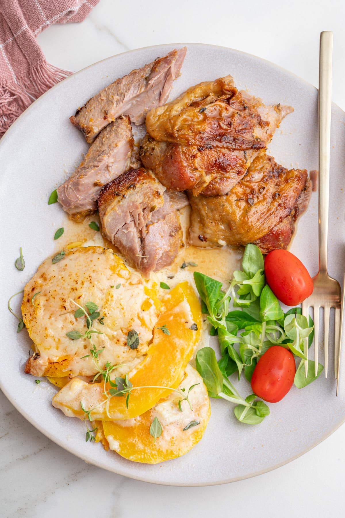 Baked turkey drumsticks on a beige plate with roasted butternut squash and salad.