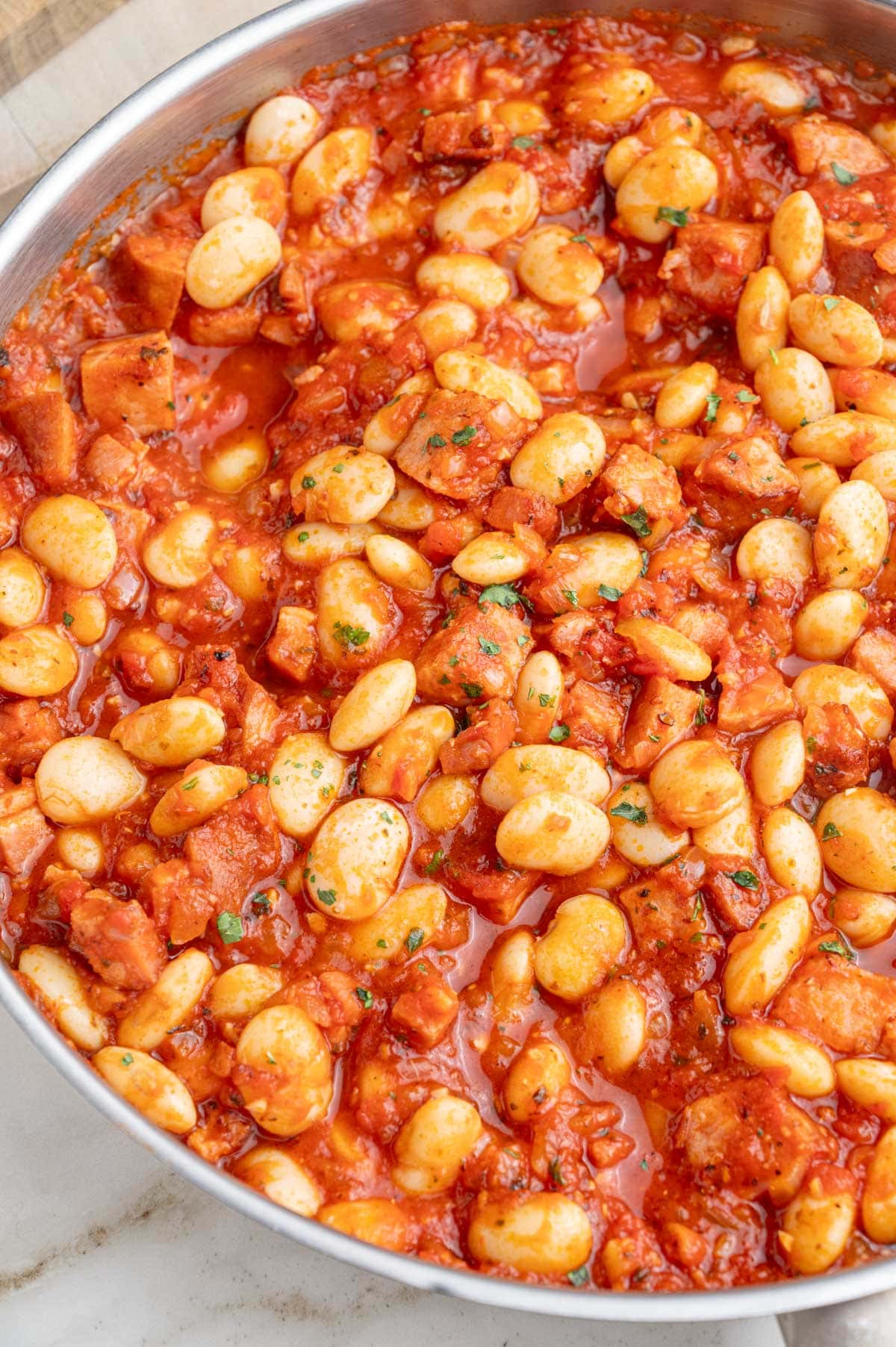 A close-up photo of Polish beans and sausage in a frying pan.