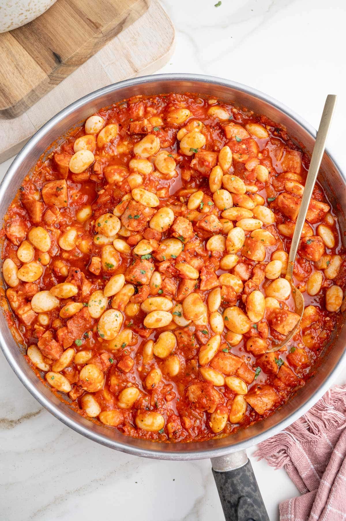 An overhead photo of Polish beans and sausage in a frying pan.