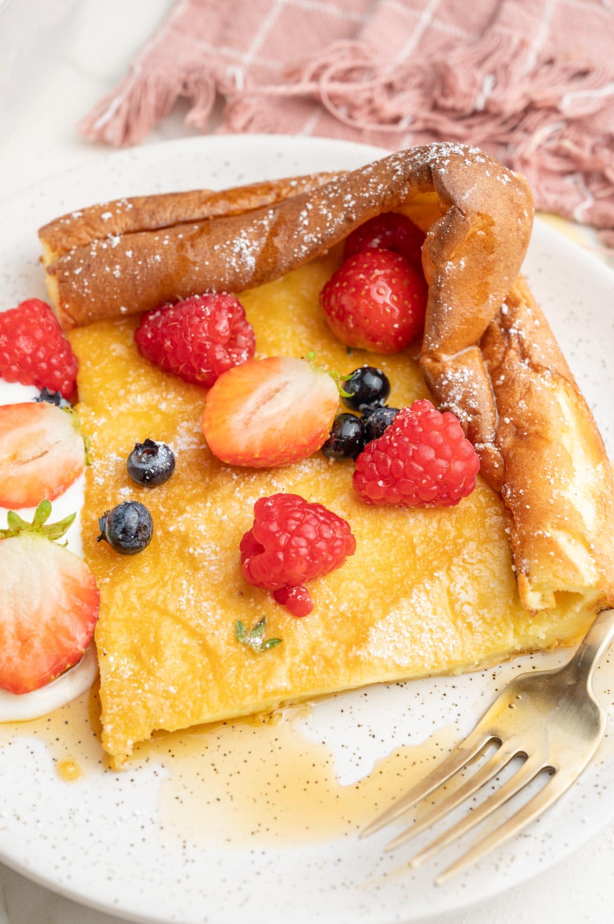 One serving of a Durch Baby pancake on a white plate with berries on top.