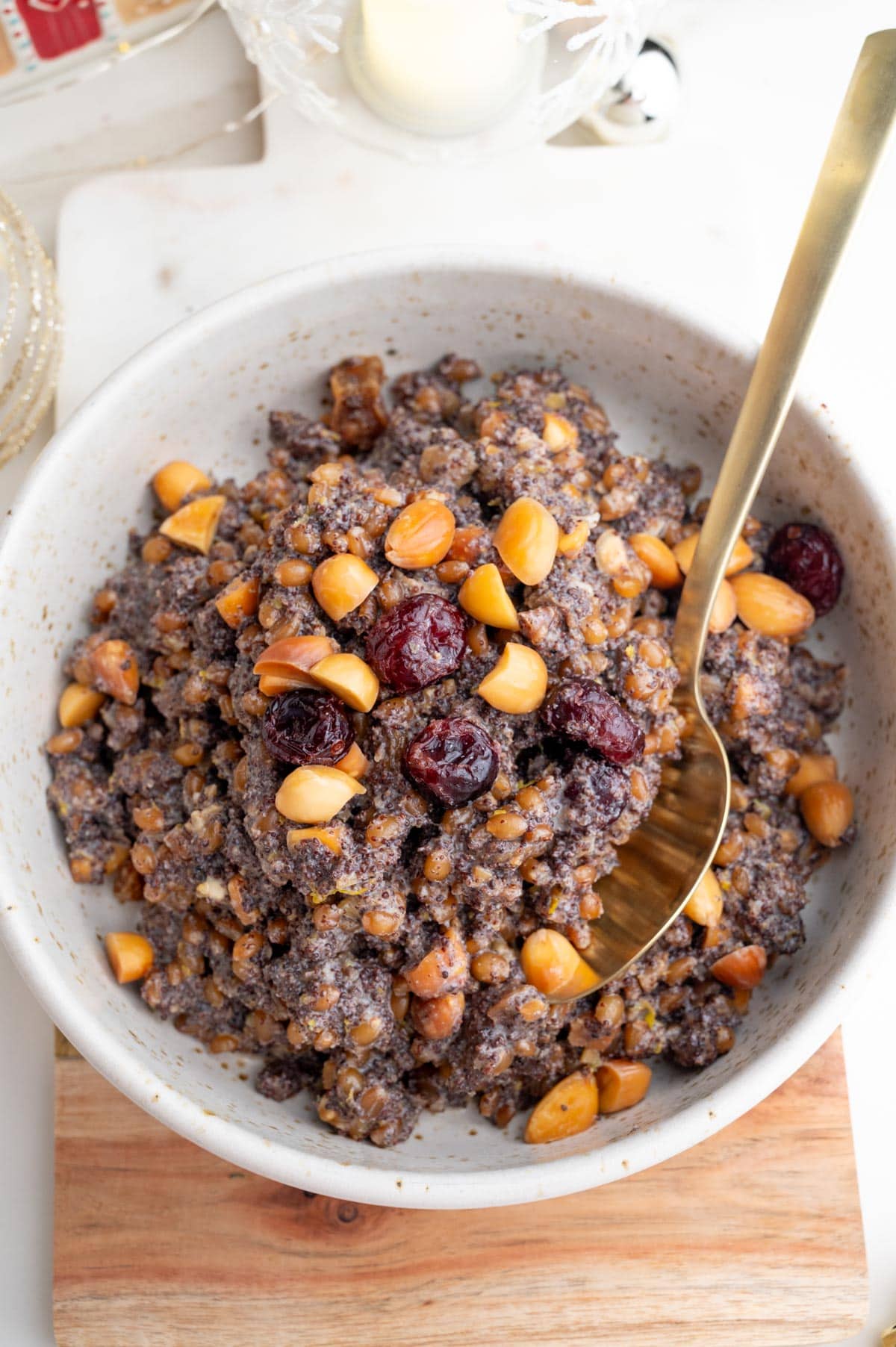 An overhead photo of Kutia in a white bowl topped with nuts. Christmas decorations in the background.