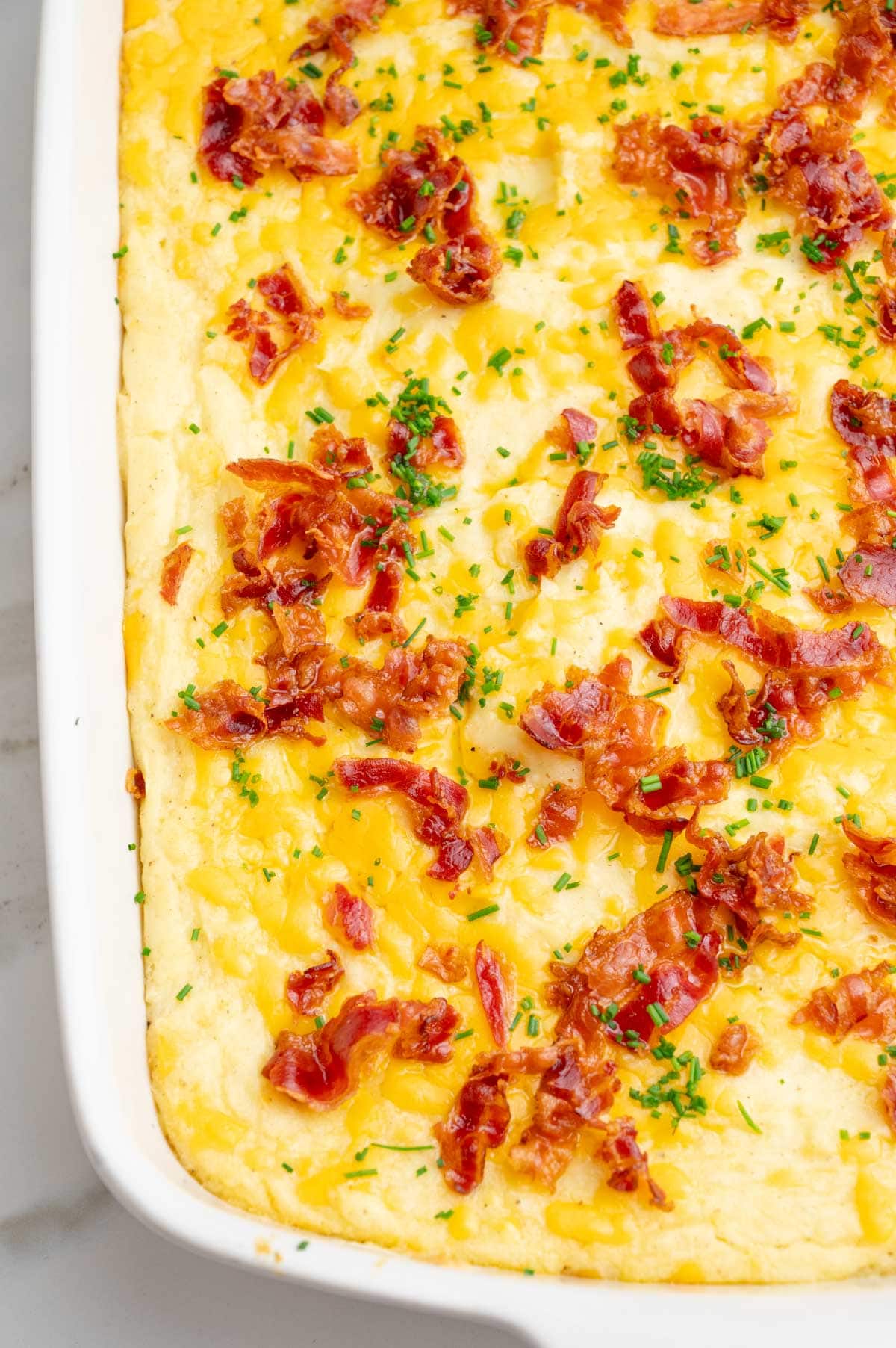 Loaded mashed potato casserole in a white baking dish.