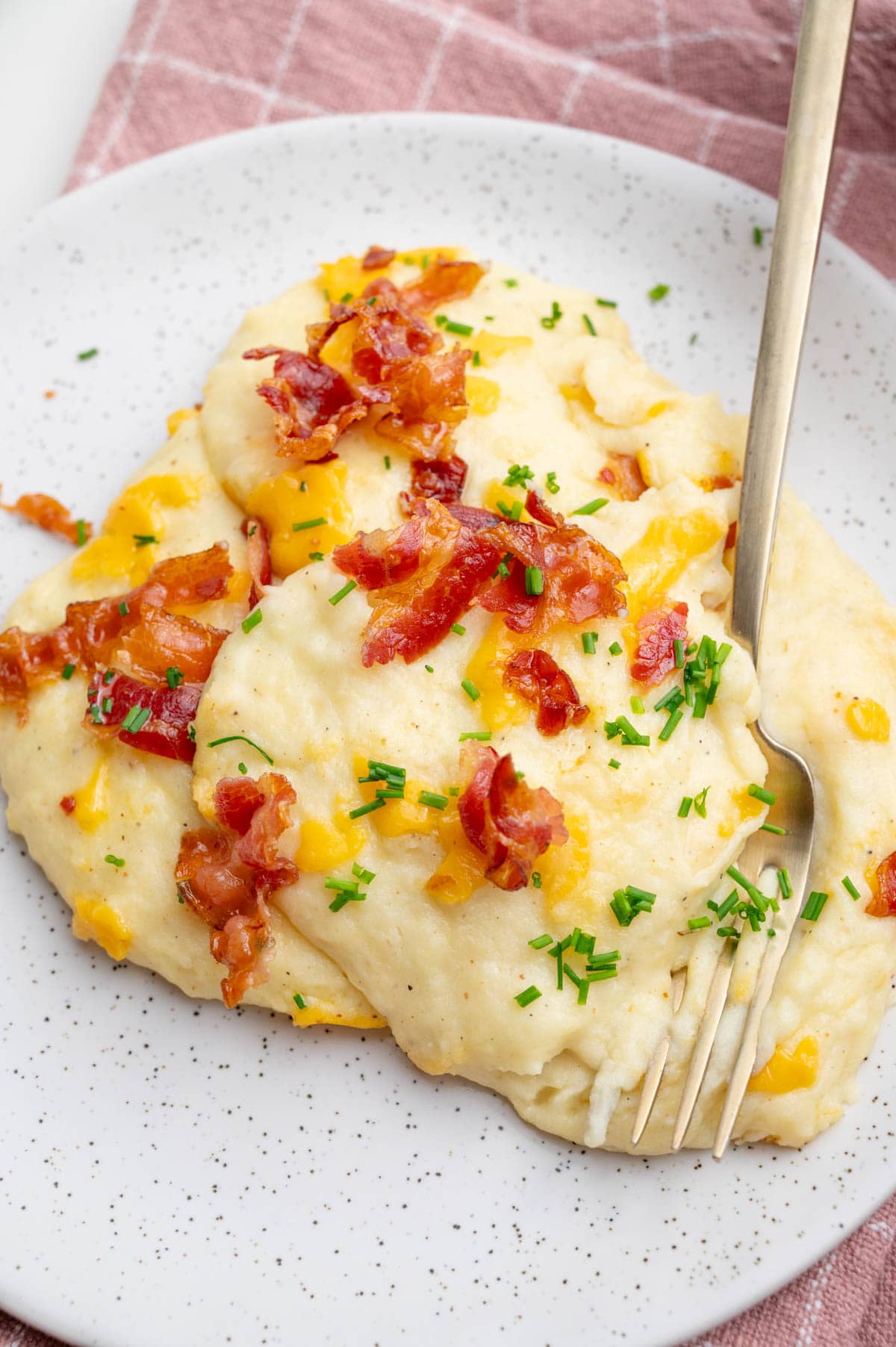 One serving of loaded mashed potato casserole on a white plate.