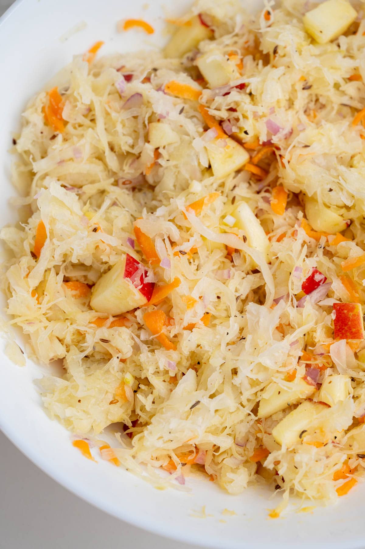 A close up photo of sauerkraut salad in a white bowl.