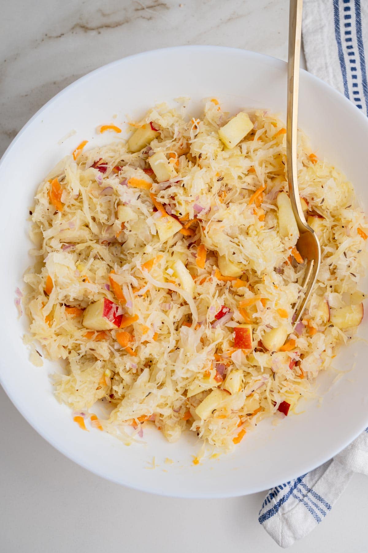 An overhead photo of sauerkraut salad in a white bowl.