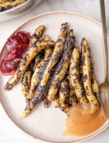 Mohnudeln with apple sauce and plum compote on a beige plate.