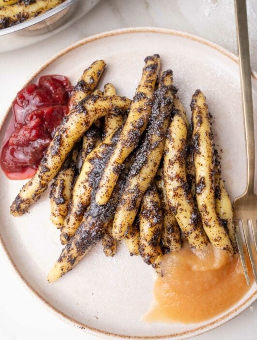 Mohnudeln with apple sauce and plum compote on a beige plate.