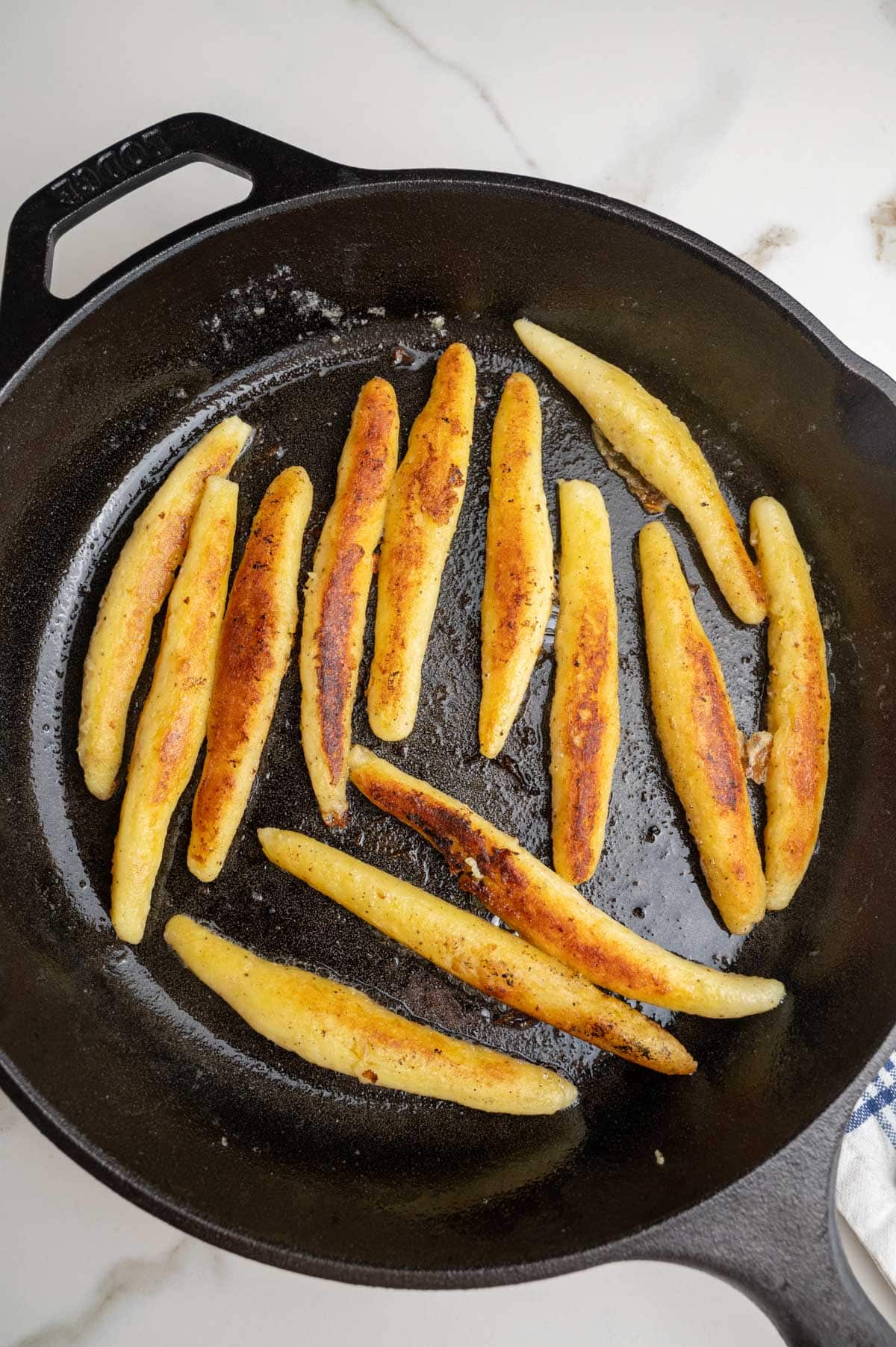 Pan-fried  golden Schupfnudeln in a black cast iron pan.