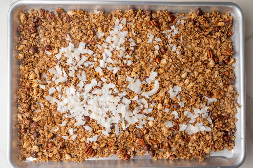 Partially baked granola with coconut chips on top.
