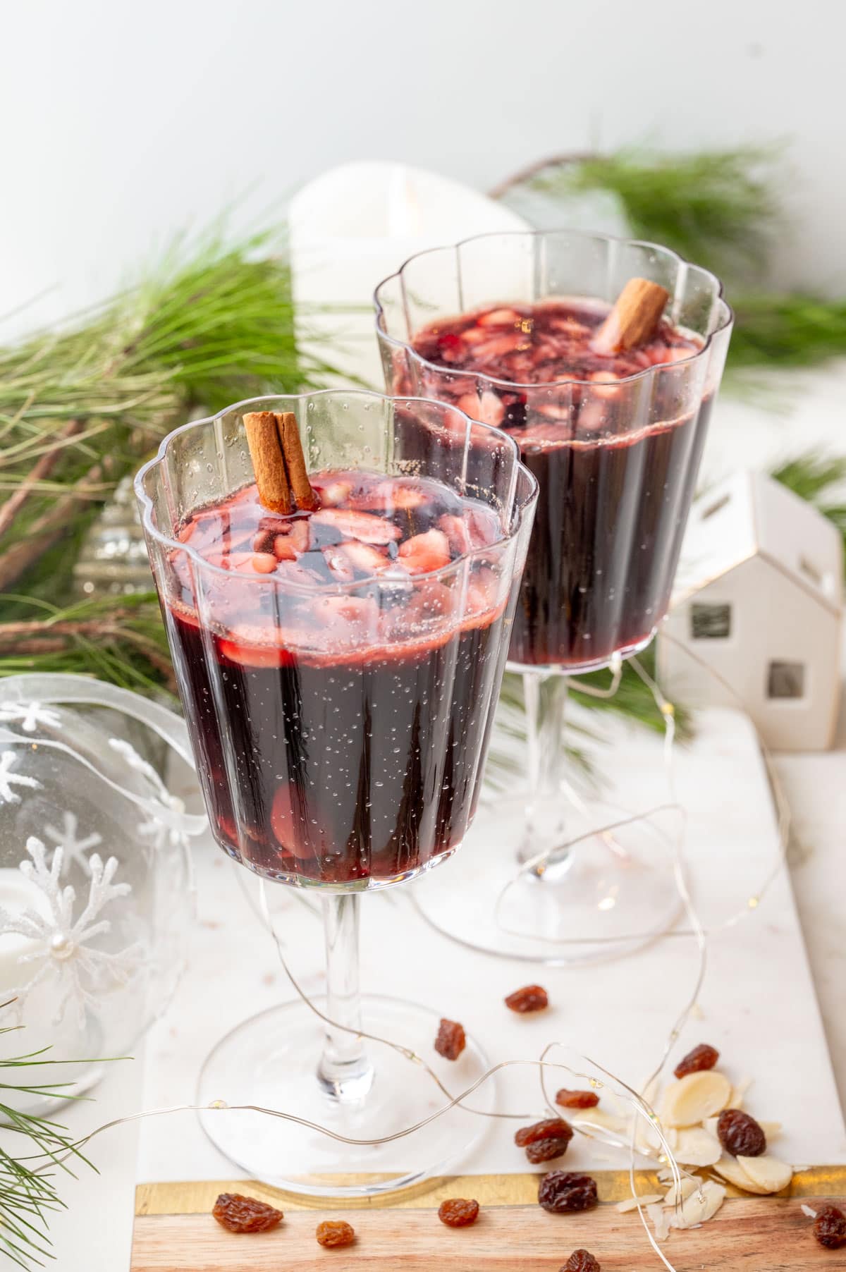 Two glasses with Glogg on a white board. Christmas decorations in the background.