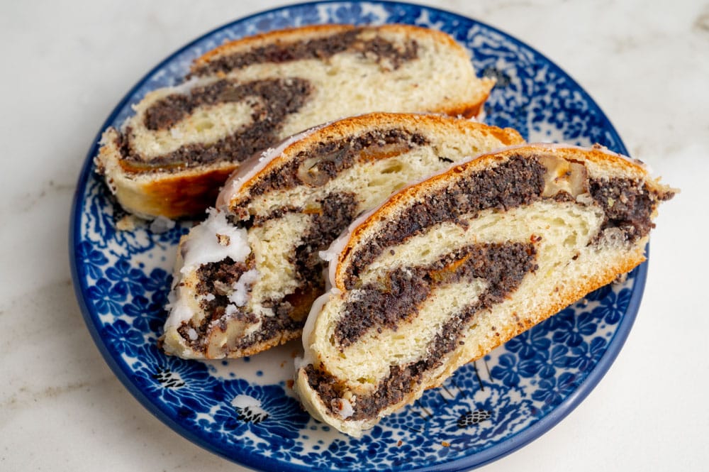 Three slices of poppy seed roll on a blue plate.