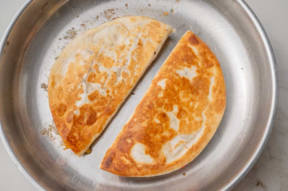 Pan-fried chicken quesadillas in a frying pan.