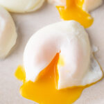 A poached egg with runny egg yolk on a beige plate.