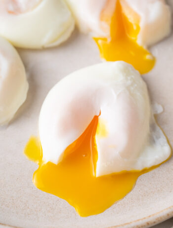 A poached egg with runny egg yolk on a beige plate.