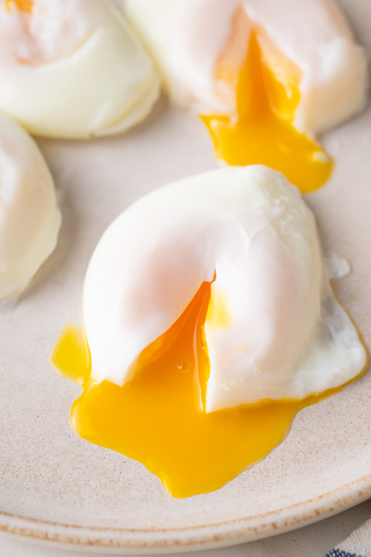 Poached egg with runny egg yolks on a beige plate.