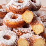 Polish cheese donuts (oponki) sprinkled with powdered sugar on a cooling rack.