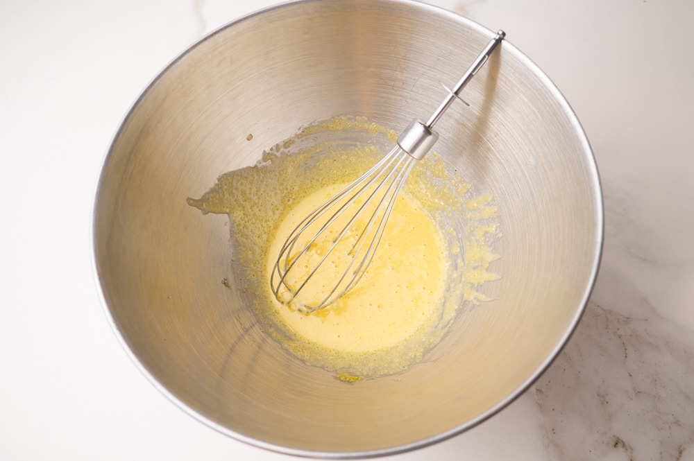Whisked eggs and sugar in a metal bowl.