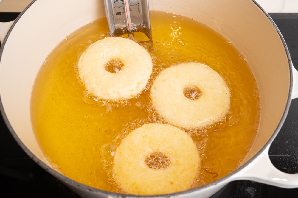 Oponki donuts are being fried in a large pot filled with oil.