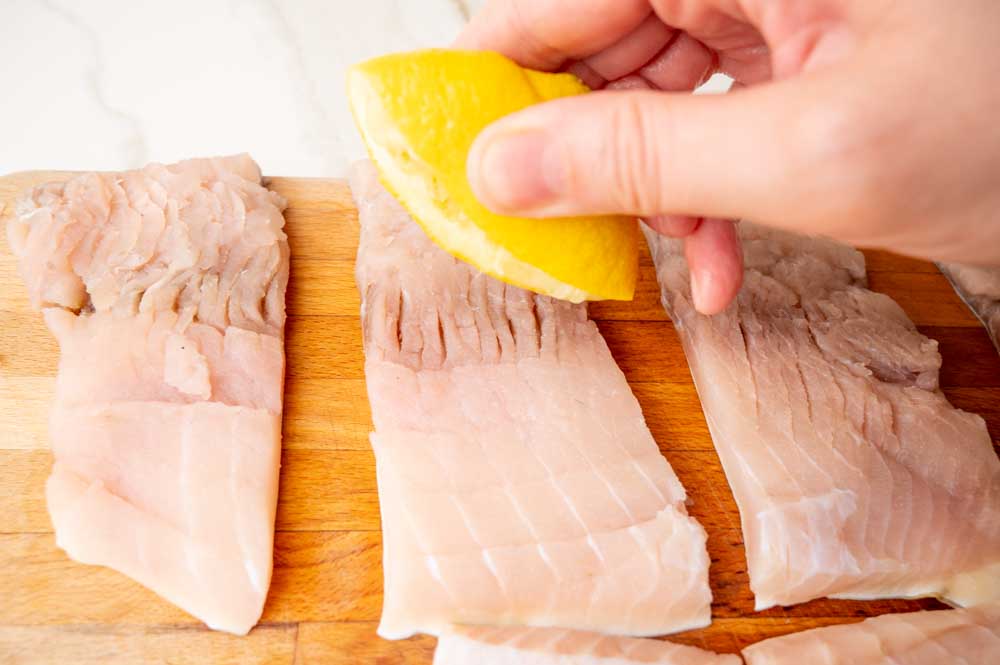 Carp fillets are being sprinkled with lemon juice.