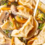 A close up photo of potsticker soup in a white bowl.