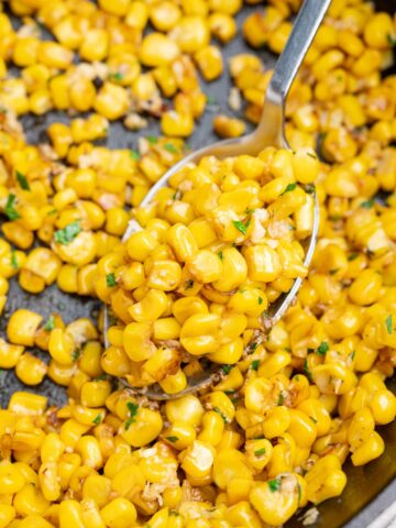 A close up photo of sauteed corn in a cast iron pan.