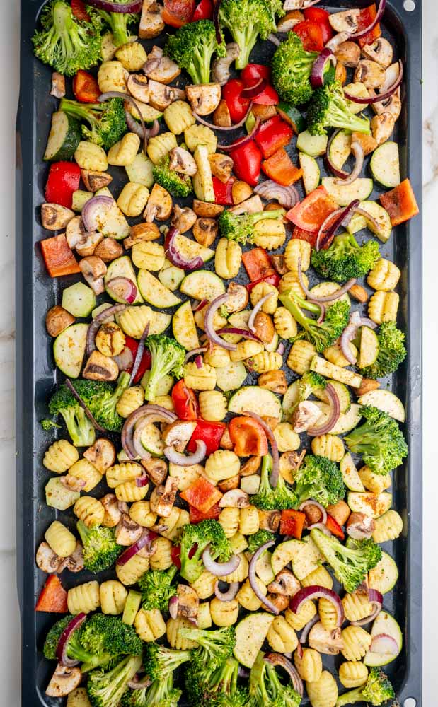 Seasoned gnocchi and vegetables on a baking sheet.