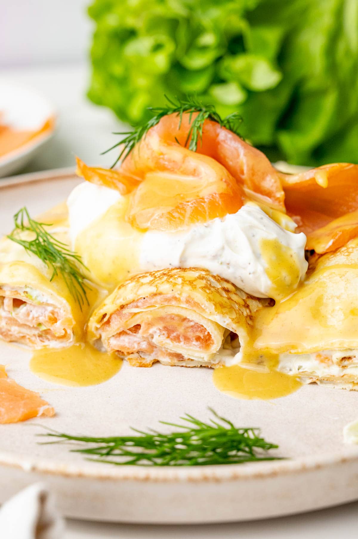 Smoked salmon crepes cut in half on a beige plate.