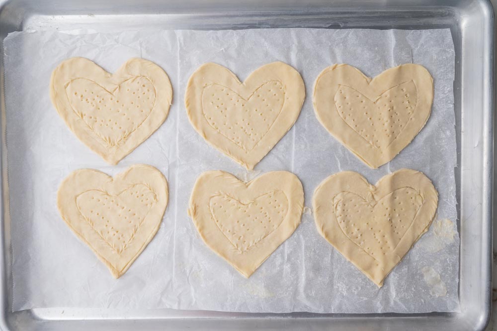 Heart-shaped puff pastry on a parchment paper.