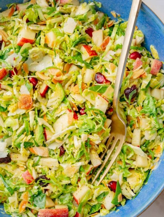 Shaved brussel sprouts salad in a blue bowl.