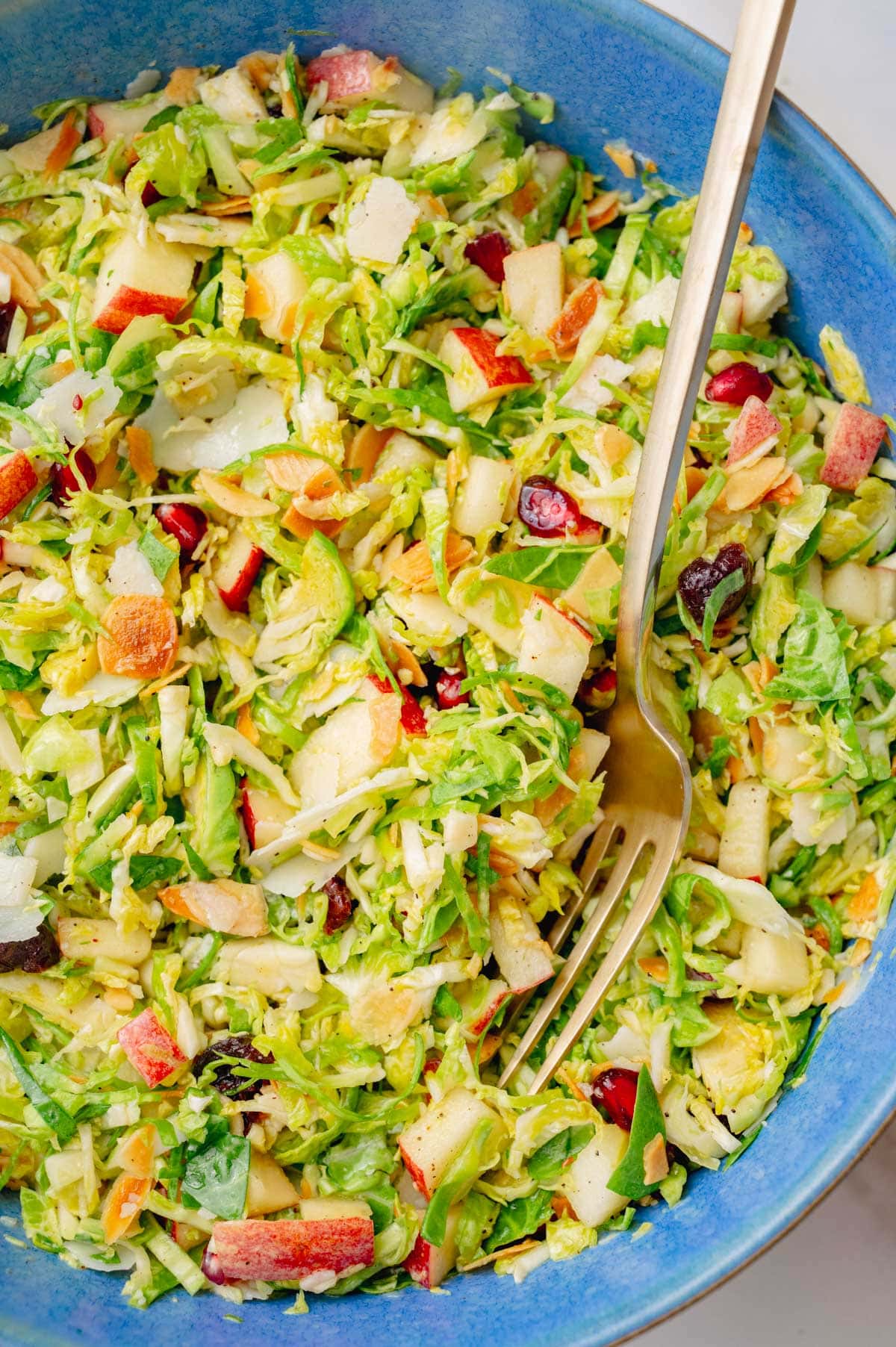 A close-up photo of shaved brussel sprout salad in a blue bowl.