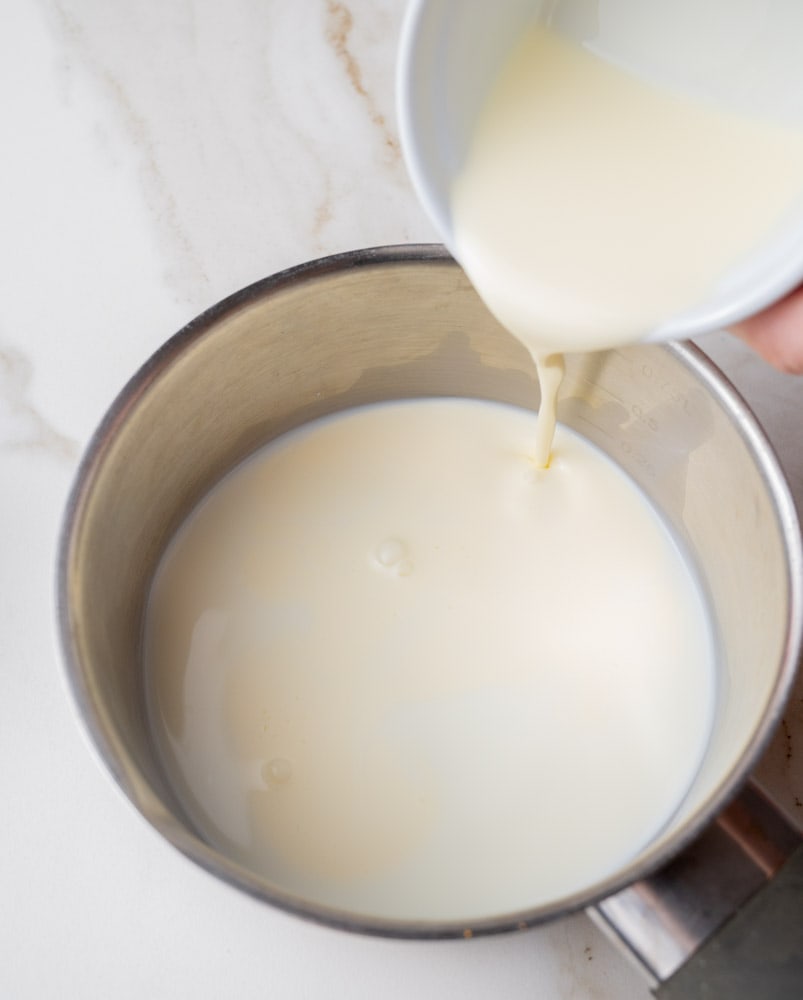 Cream is being added to a pot.